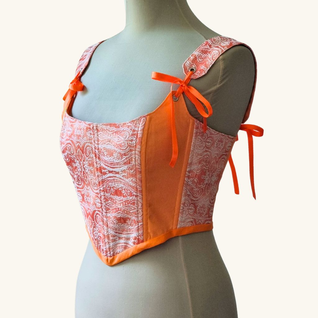 Korset na maneken gledka otstrani rachno izraboten ot oranjev pamuk s oranjevi pandelki i metalni kapsi