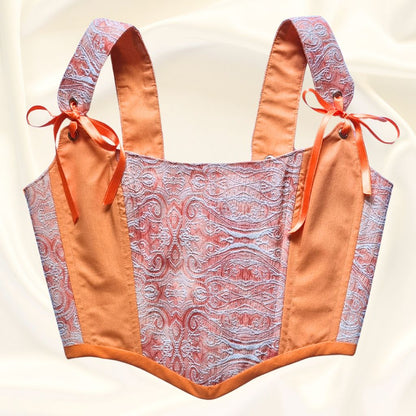 Korset gledka otpred oranjev rachno izraboten ot pamuk s oranjevi sateneni pandelki i mesingovi kapsi